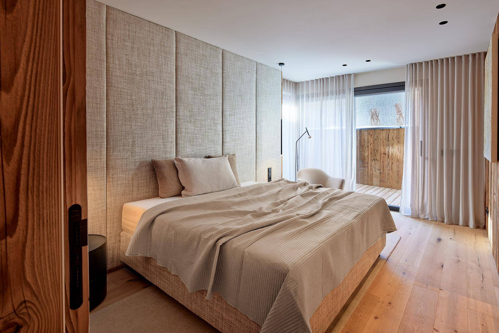Helles Schlafzimmer mit Holzboden, bequemen Bett und Zugang zu einem privaten Außenbereich.