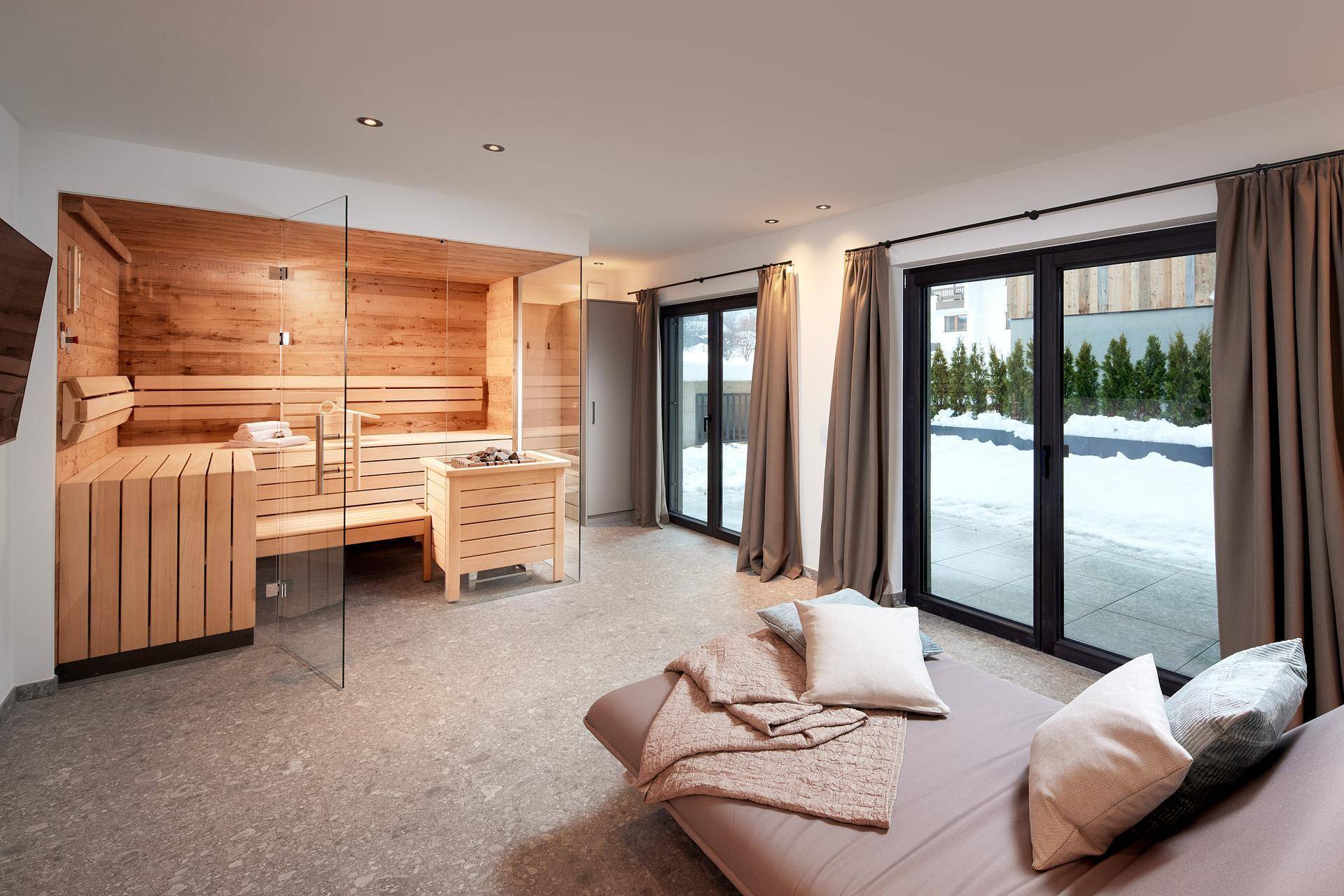 Entspannungsbereich mit moderner Sauna und Zugang zu einem verschneiten Außenbereich.