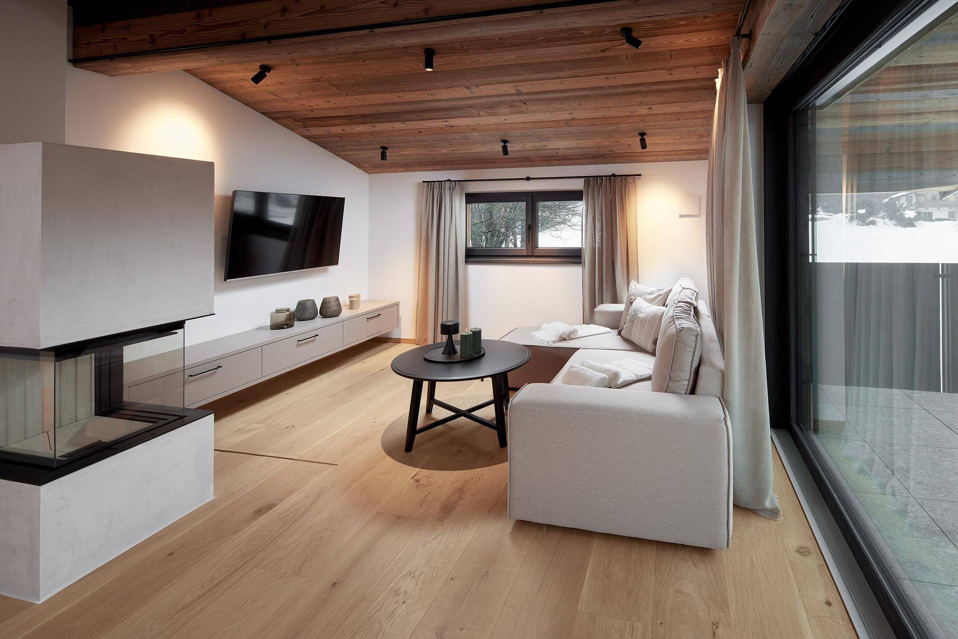 Gemütliches Wohnzimmer mit Kamin, Holzboden und Zugang zu einem Außenbereich.