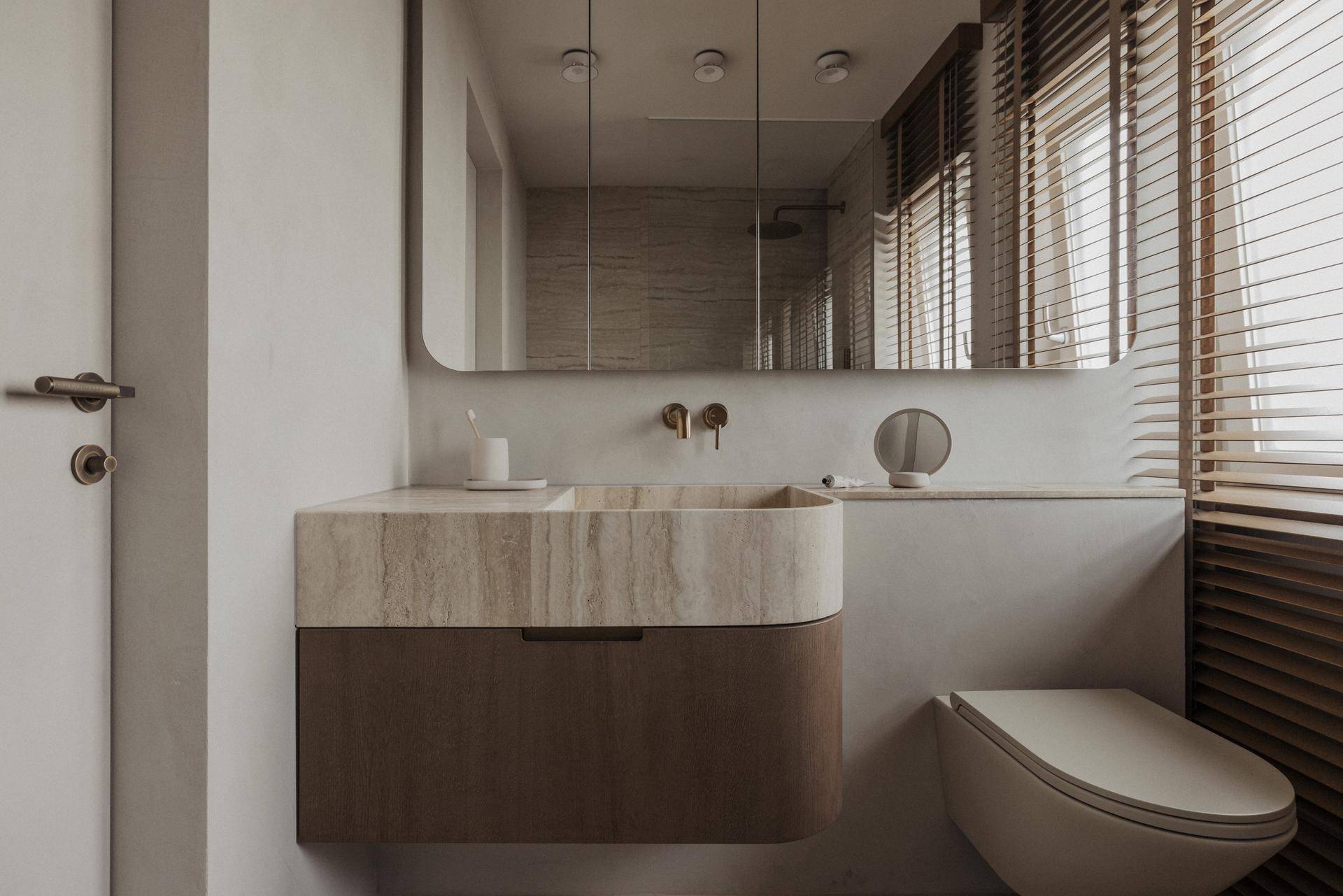 Elegantes WC mit modernem Waschbecken aus Naturstein und integriertem Spiegelschrank.