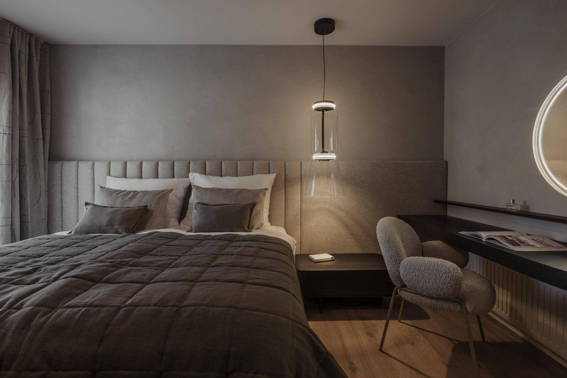 Modernes Schlafzimmer mit großem Bett, gepolstertem Kopfteil und stilvollem Schminktisch.