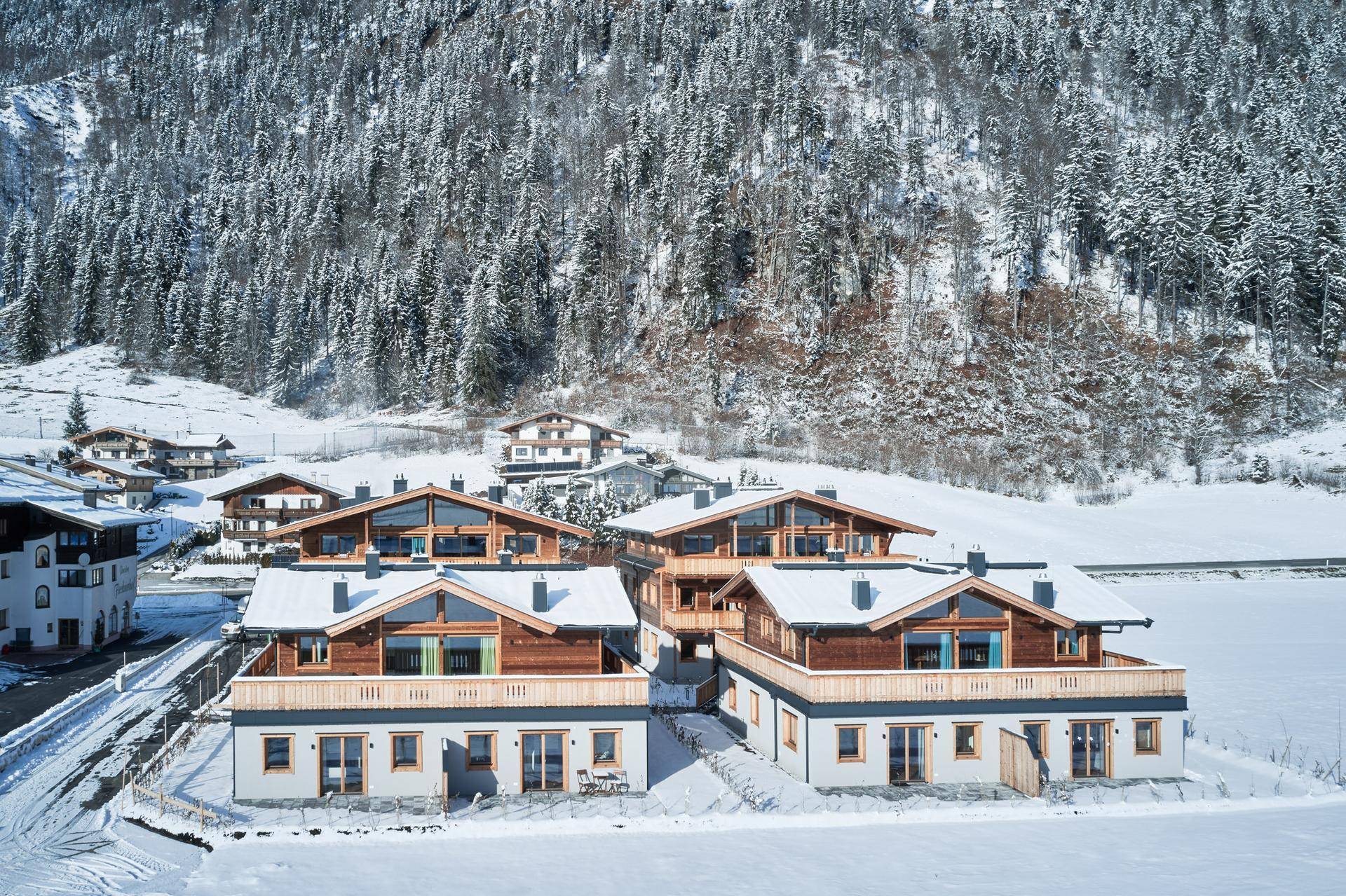 Mehrere moderne Gebäude im alpinen Stil, eingebettet in eine verschneite Berglandschaft.