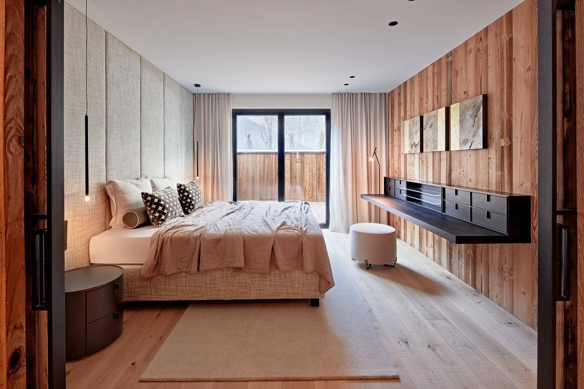Stilvolles Schlafzimmer mit Holzboden, Holzwand und einem integrierten Schreibtischbereich.