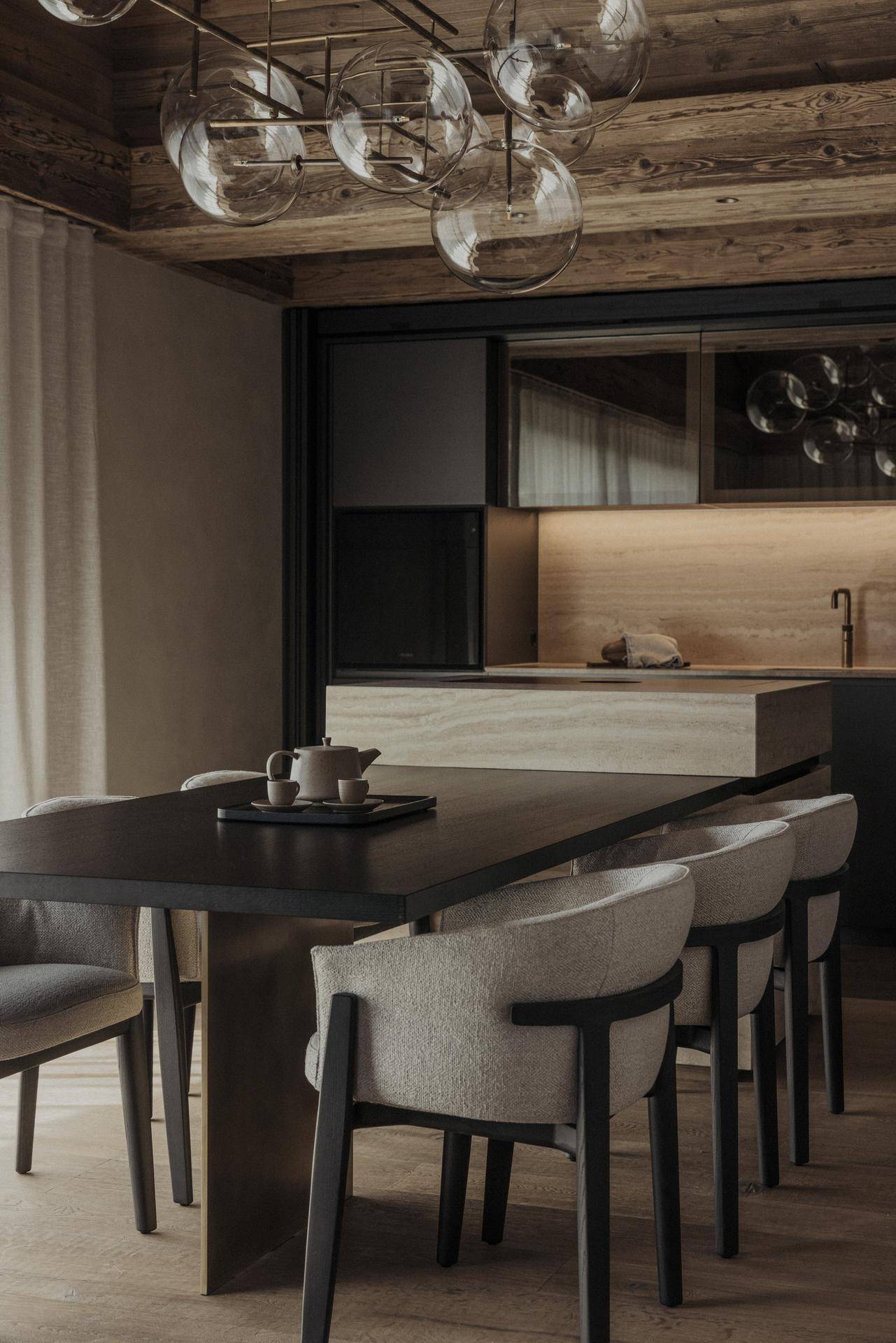 Elegante Küche mit dunklen Schränken, Holzdetails und einem Esstisch für mehrere Personen.