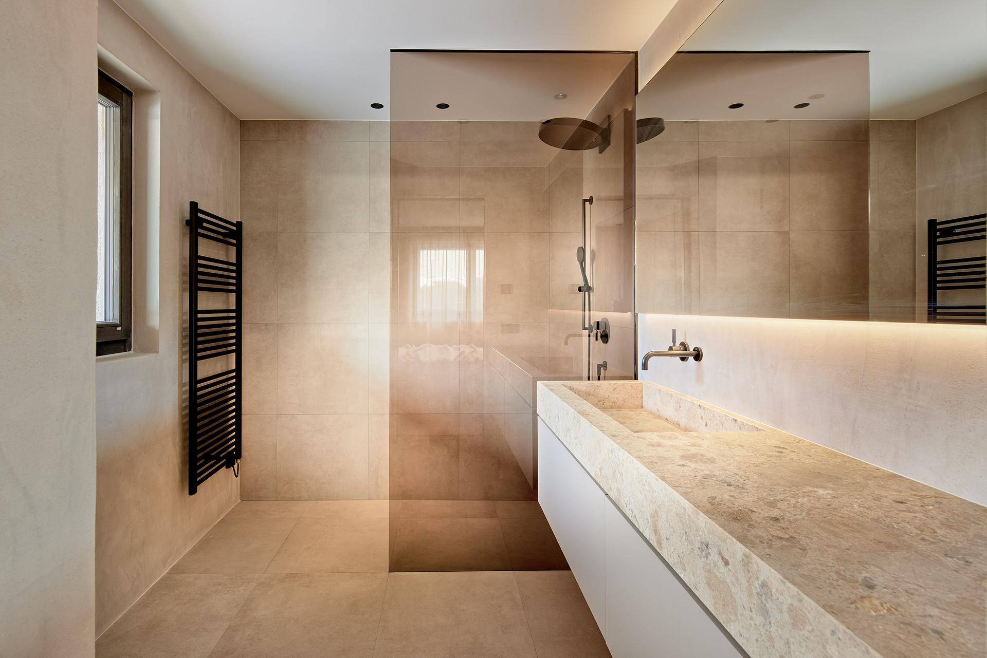 Modernes Badezimmer mit begehbarer Dusche, beheiztem Handtuchhalter und großem Spiegel.