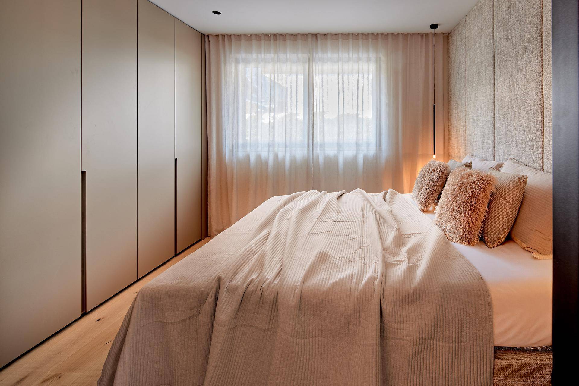 Modernes Schlafzimmer mit Einbauschränken, großem Fenster und Bergblick.