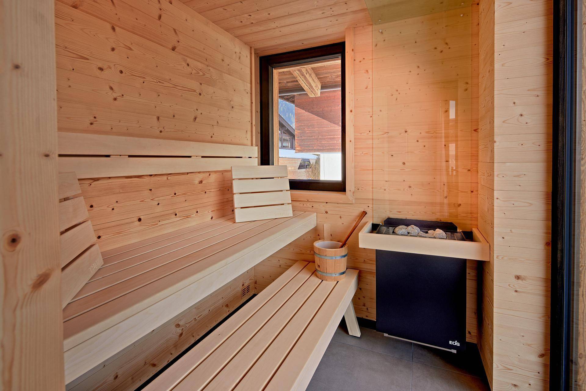 Traditionelle Holzsauna mit Bänken und Saunaofen, ideal zur Entspannung.