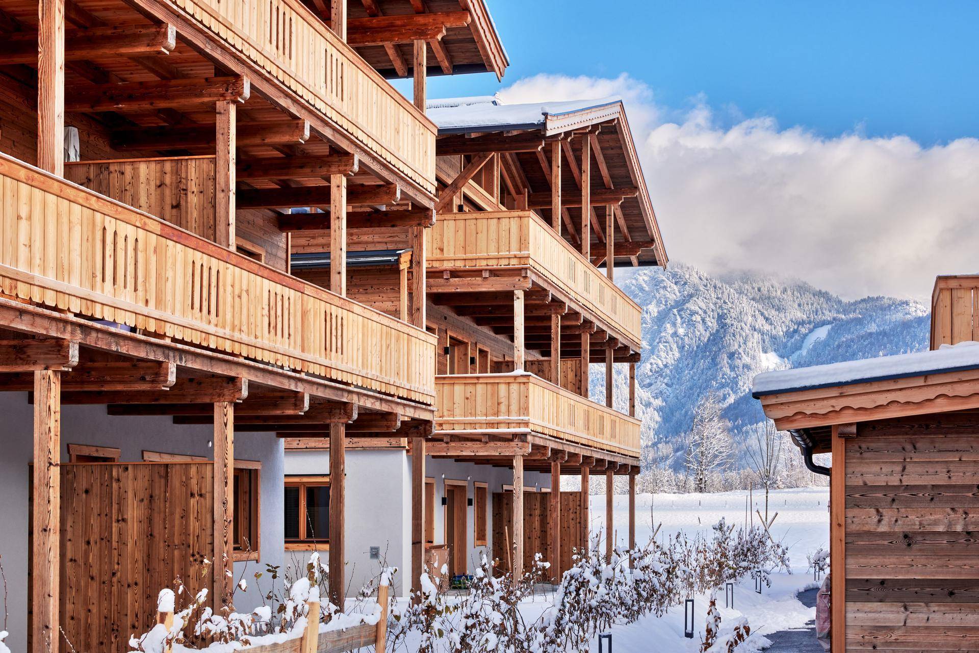 Traditionelle Holzfassade mit mehreren Balkonen und Blick auf die schneebedeckten Berge.