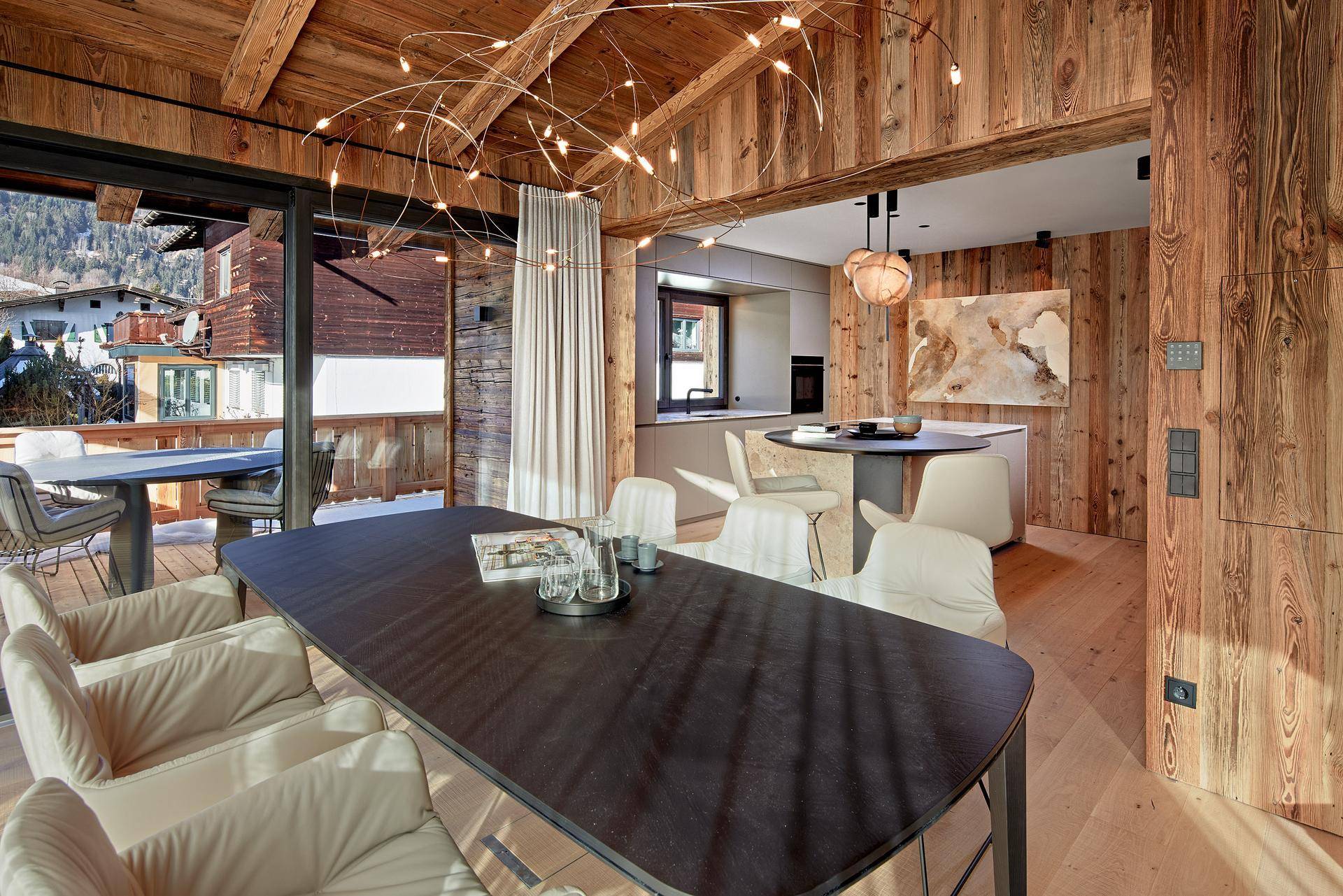 Moderner Essbereich mit Holzbalkendecke, Designerleuchte und Zugang zur Terrasse.