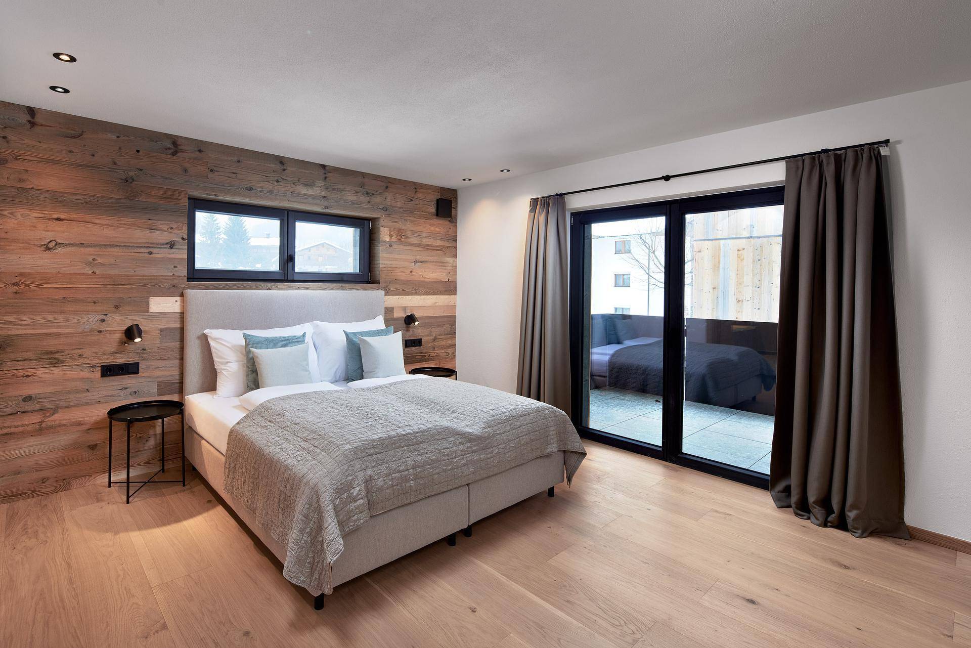 Schlafzimmer mit Holzwand, Doppelbett und direktem Zugang zu einem Außenbereich.
