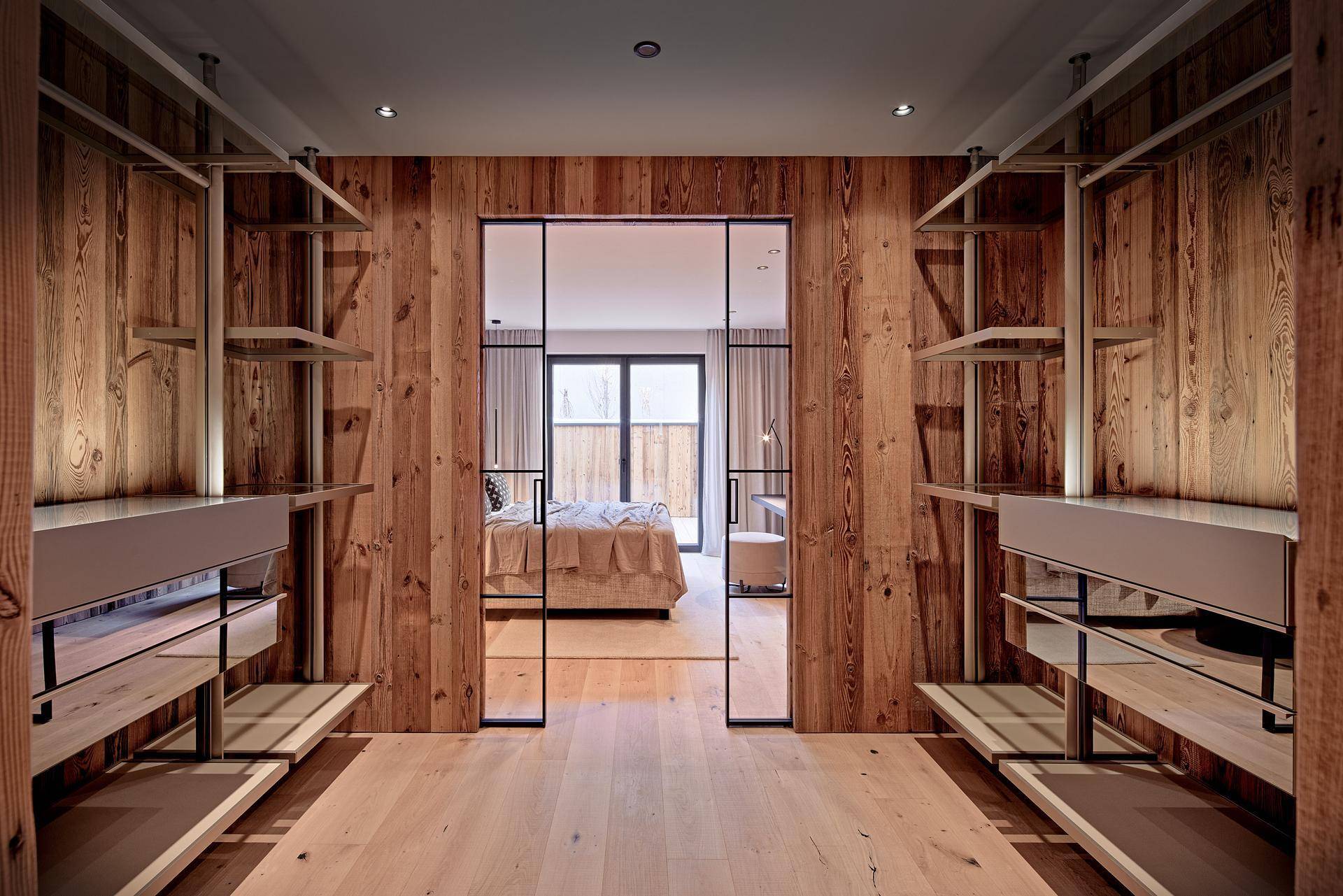 Geräumiger begehbarer Kleiderschrank mit Holzwänden und Blick ins Schlafzimmer.