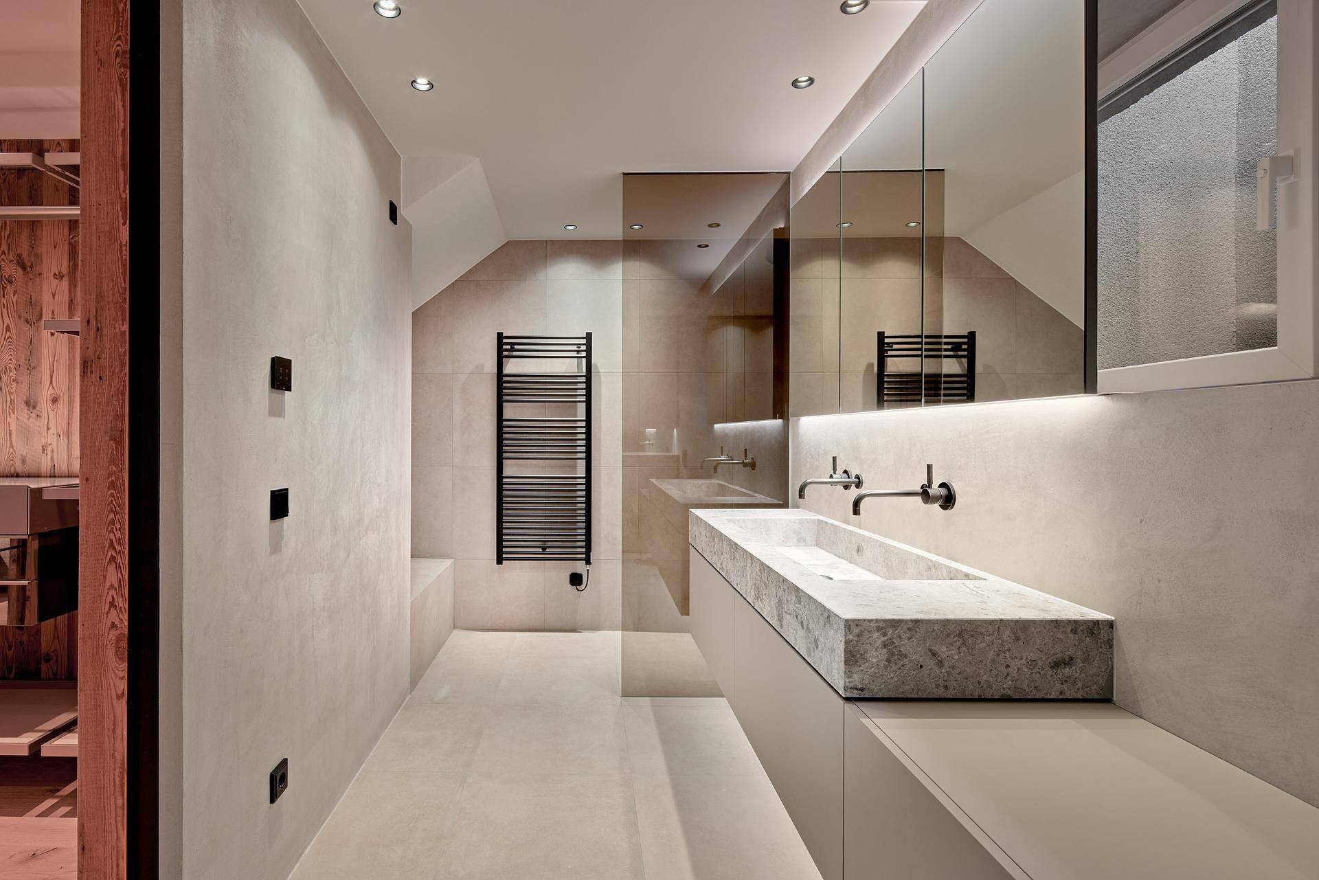 Elegantes Badezimmer mit Doppelwaschbecken aus Stein, beheiztem Handtuchhalter und modernen Armaturen.