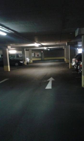 Geräumige Tiefgarage mit vielen Parkplätzen und Richtungspfeil auf dem Boden.