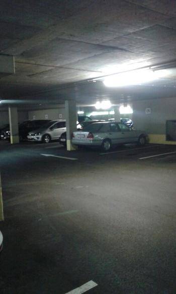 Dunkle Tiefgarage mit geparkten Autos und Betonpfeilern.