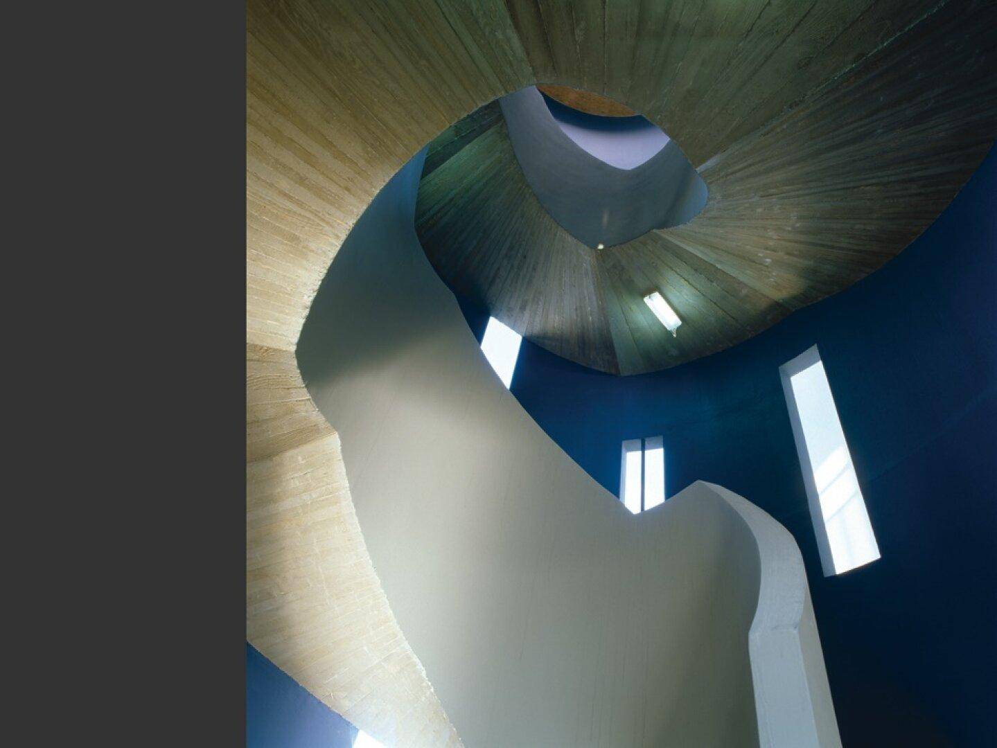 Architektonisch anspruchsvolles Treppenhaus mit geschwungenen Formen und natürlichem Lichteinfall von oben.