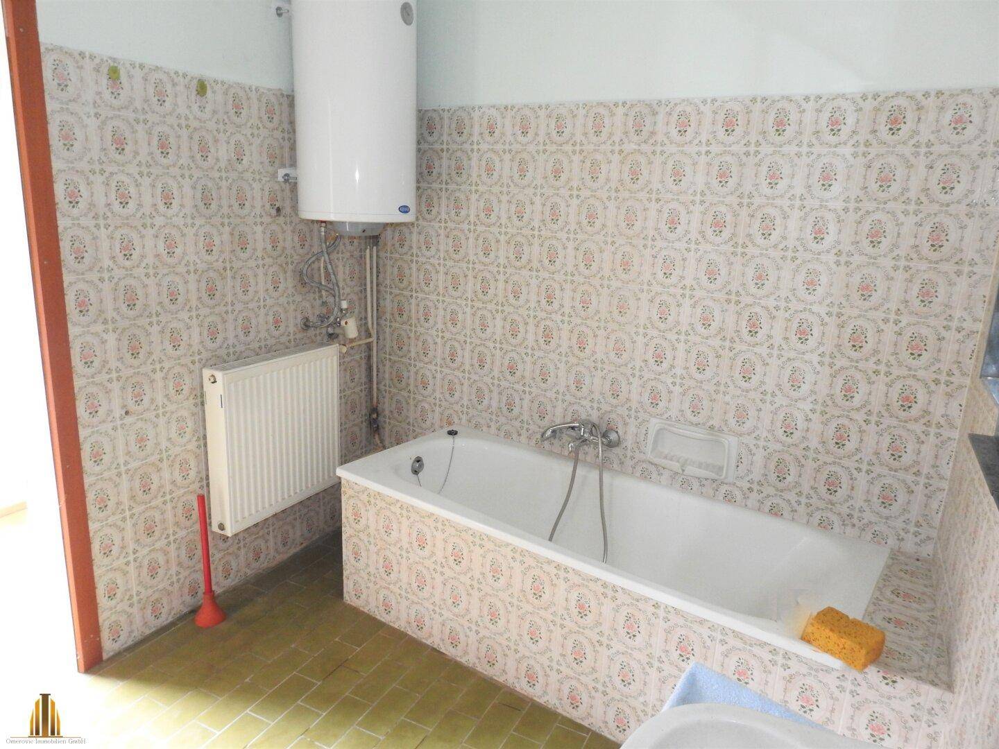 Badezimmer mit Badewanne, Boiler und traditionellen Fliesen, die einen älteren Stil aufweisen.