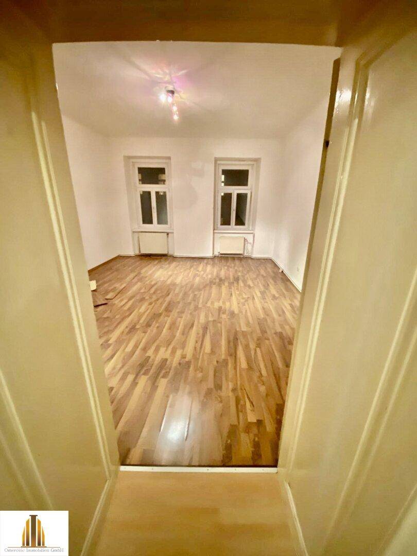Geräumiger, leerer Raum mit Laminatboden und zwei Fenstern, ideal für Wohnzwecke und vielseitig nutzbar.
