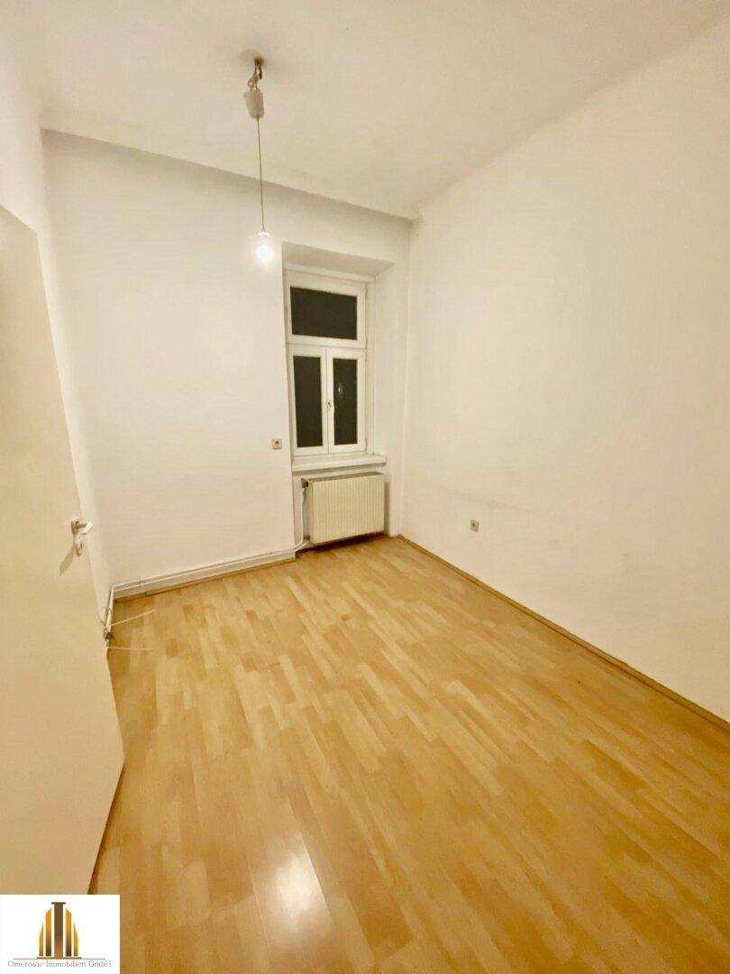 Kleinerer Raum mit Holzfußboden und einem Fenster, geeignet als Schlaf- oder Arbeitszimmer.