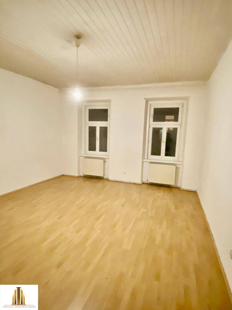Heller Raum mit Holzfußboden und zwei Fenstern, bietet vielseitige Nutzungsmöglichkeiten und natürliches Licht.