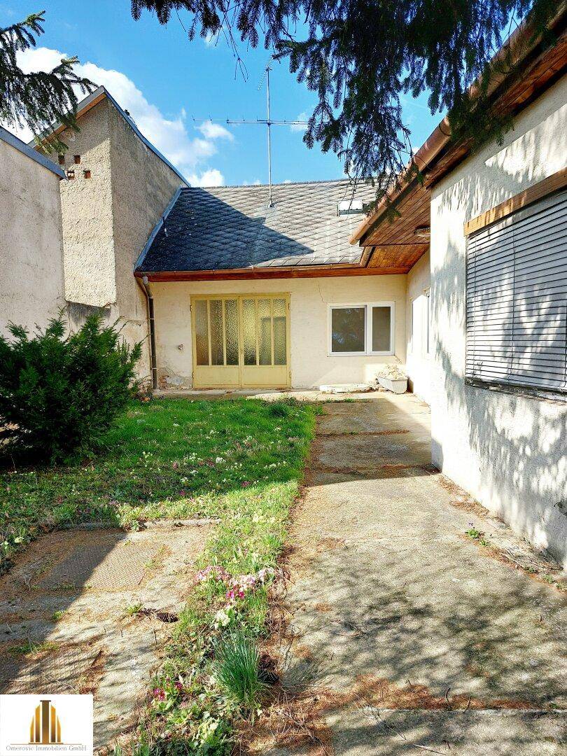 Rückansicht des Hauses mit kleiner Rasenfläche und Zugang zu einem überdachten Bereich.