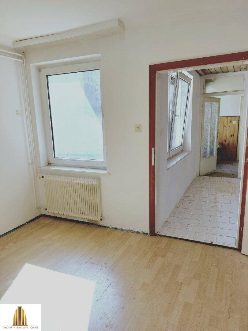 Übergangsbereich mit Parkettboden und Blick durch eine Tür in einen gefliesten Flur.
