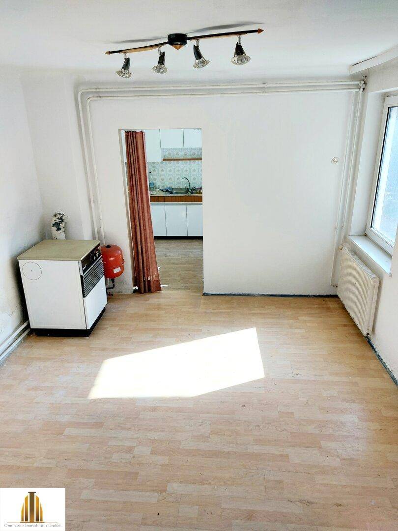 Helles Zimmer mit Parkettboden und Blick in die angrenzende Küche, ideal als Ess- oder Wohnbereich.