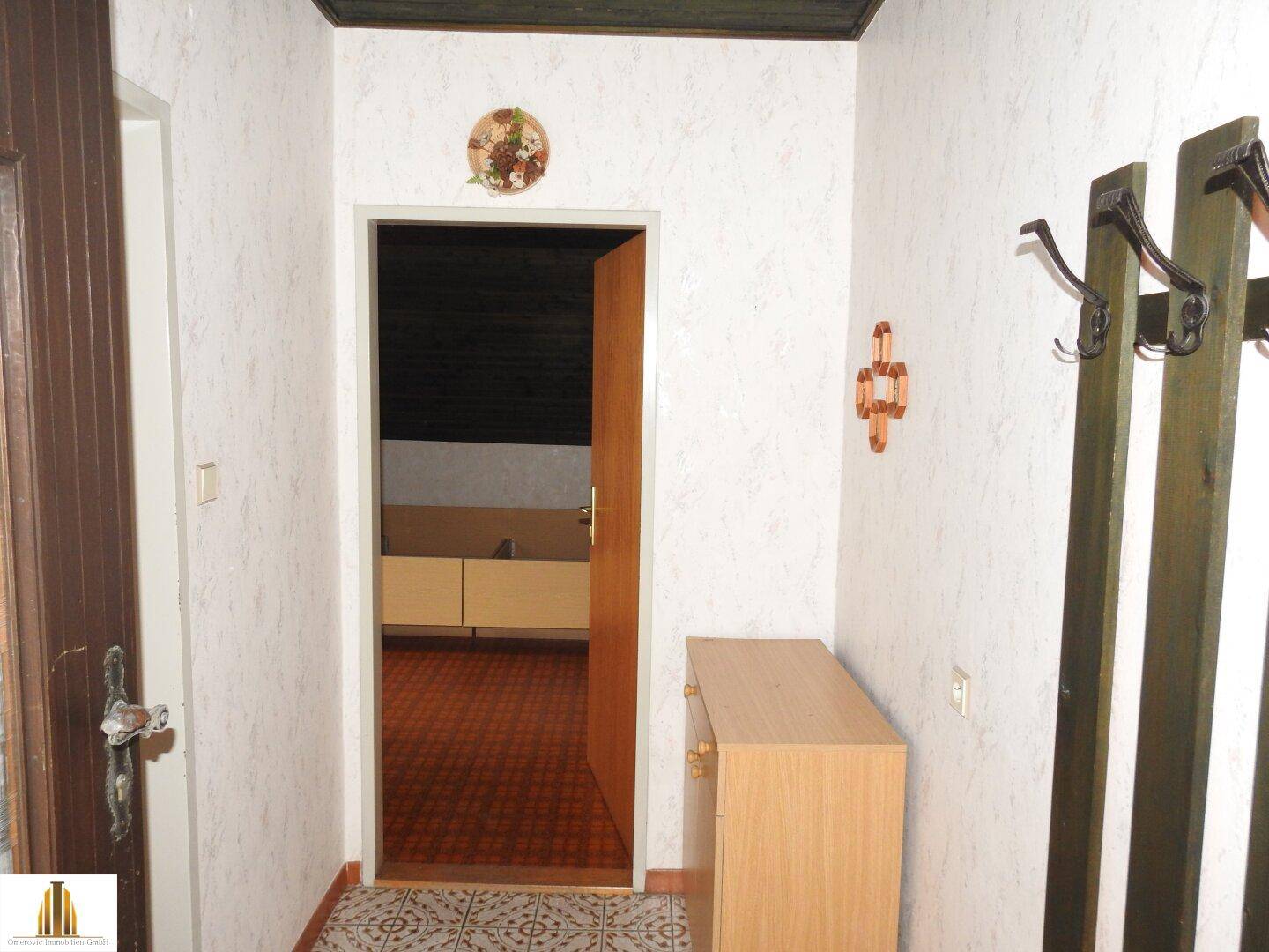 Flur mit gemusterten Fliesen, Garderobe und Zugang zu weiteren Räumen.