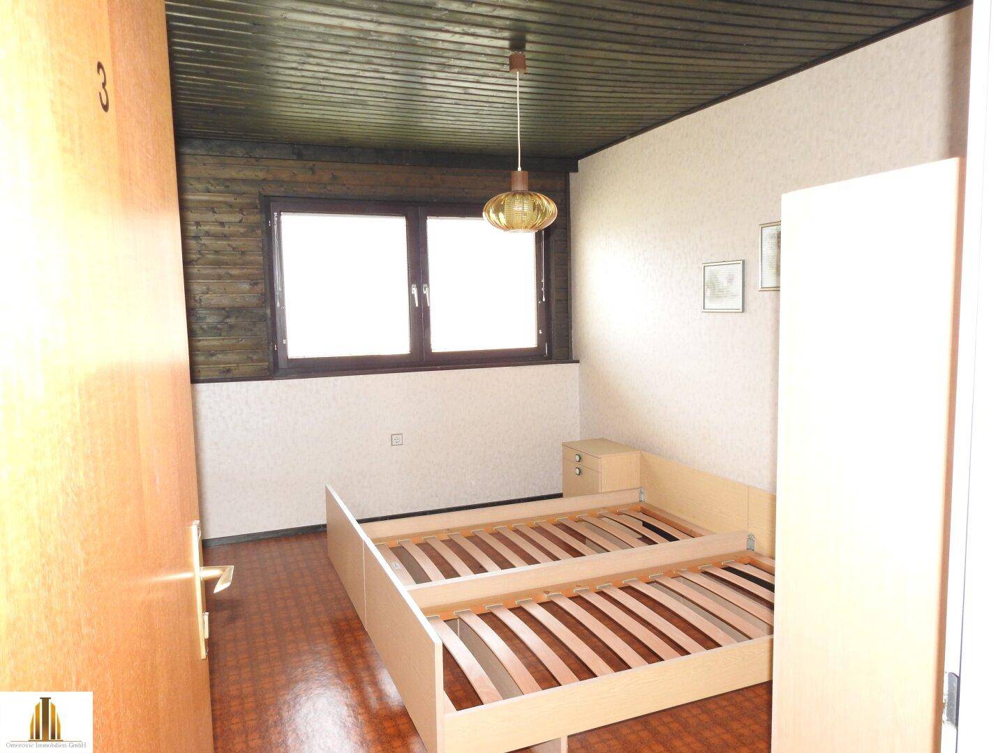 Schlafzimmer mit Holzdecke, Fenster und Platz für zwei Betten in rustikalem Stil.