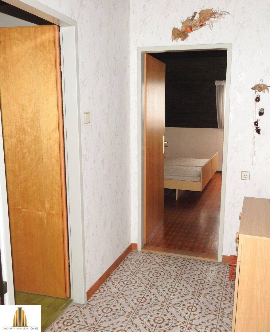 Flur mit gemusterten Fliesen und Zugang zu weiteren Räumen in schlichtem Design.