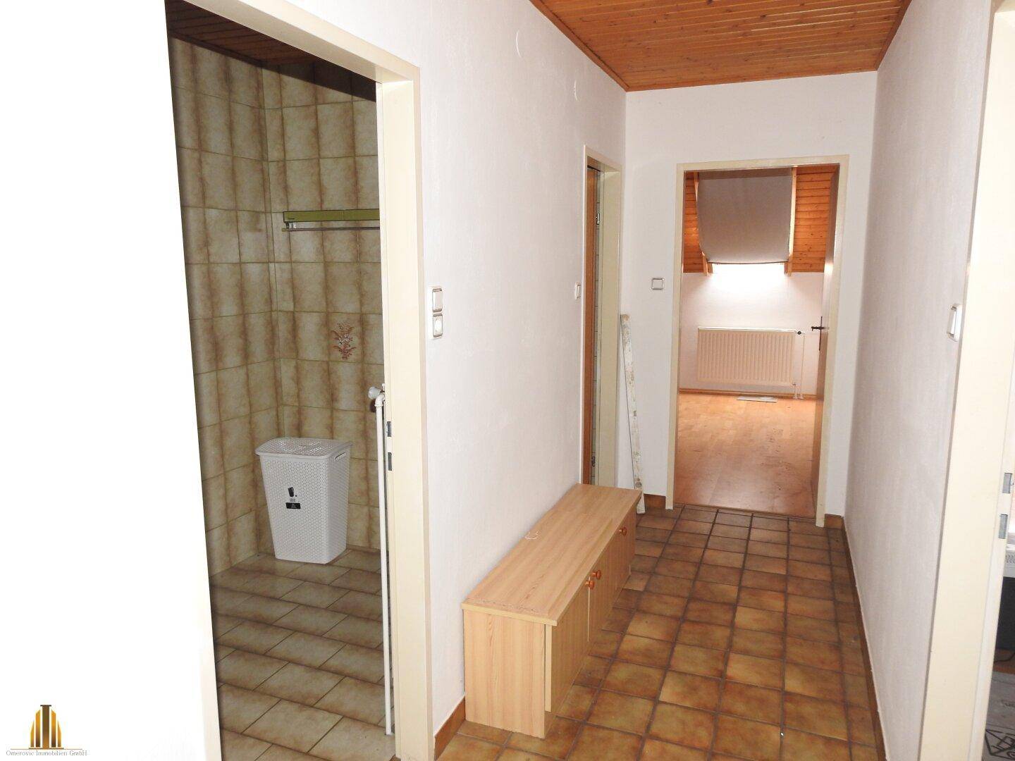 Flur mit Holzdecke, Fliesenboden und Blick in angrenzende Räume, gut erhalten.