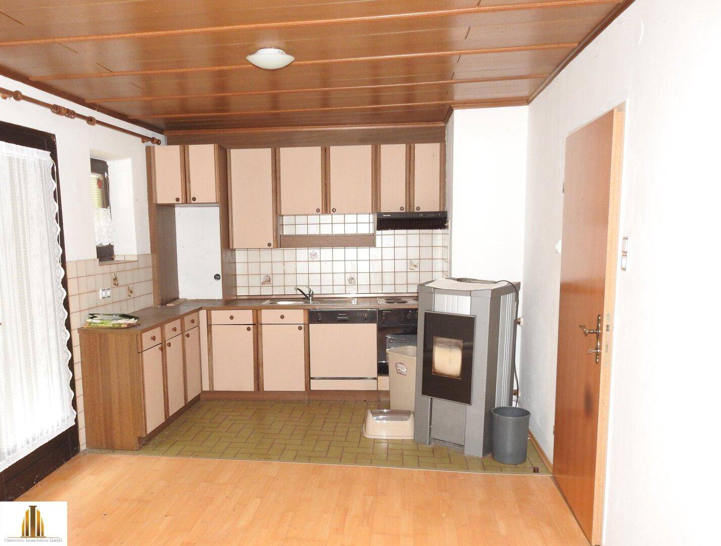 Küche mit Einbauschränken, Holzdecke und Kaminofen, funktional eingerichtet.