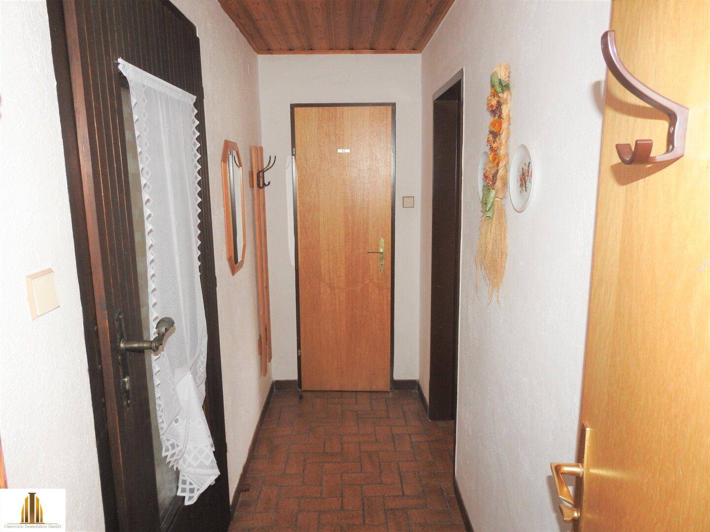 Flur mit Holzdecke, Fliesenboden und Holztüren, gut gepflegt und hell.