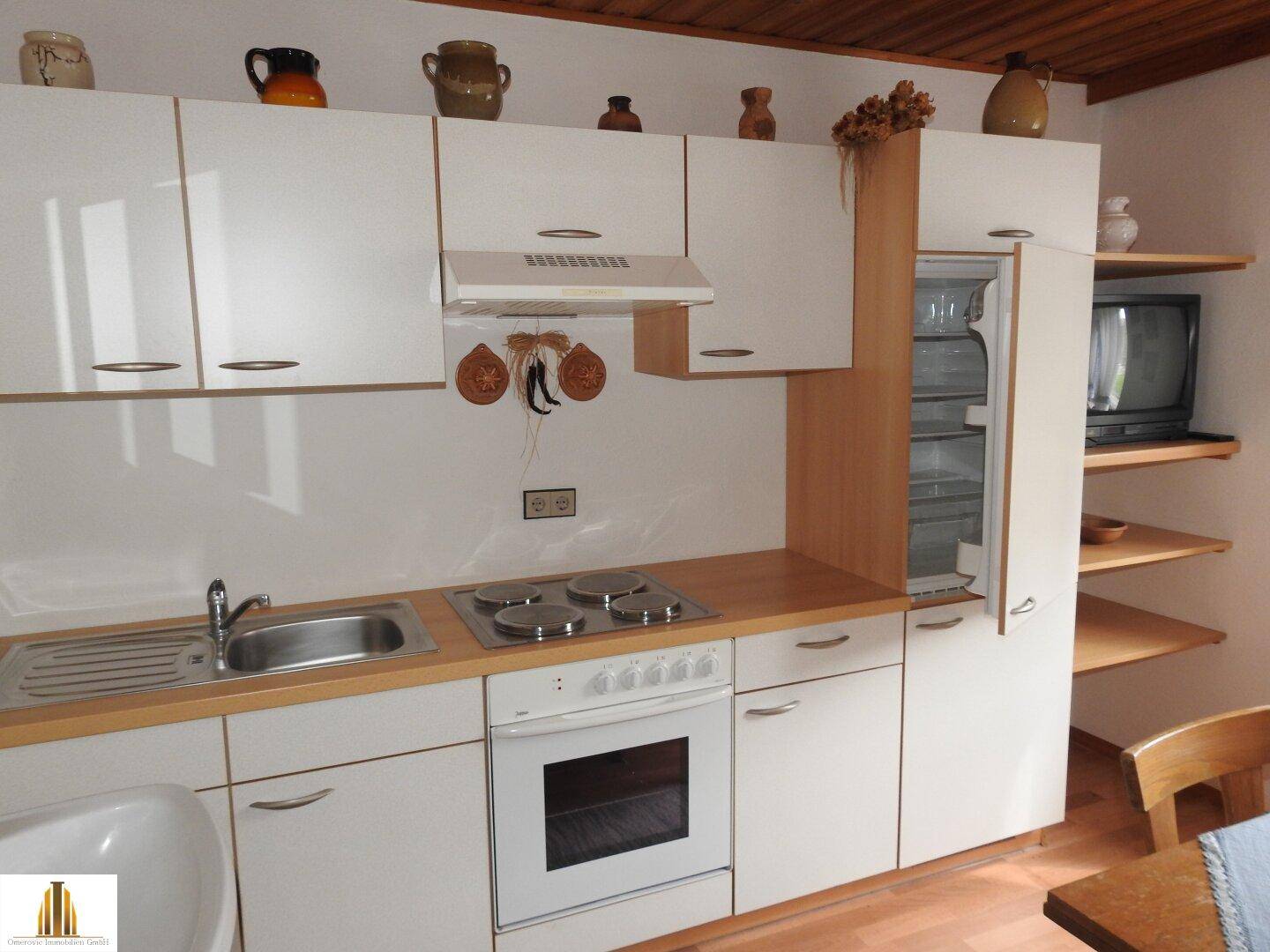 Helle Einbauküche mit weißen Schränken, Herd und Kühlschrank, praktisch und funktional.