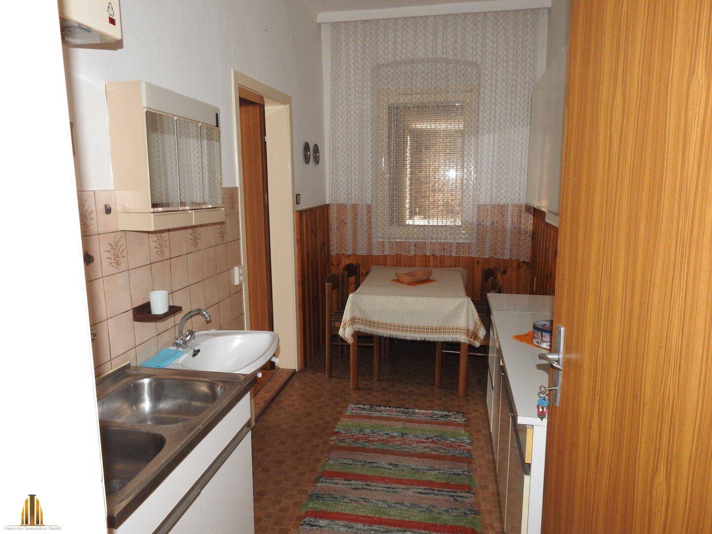 Küche mit Essbereich, Spüle und Holzverkleidung an den Wänden, gemütlich und funktional.