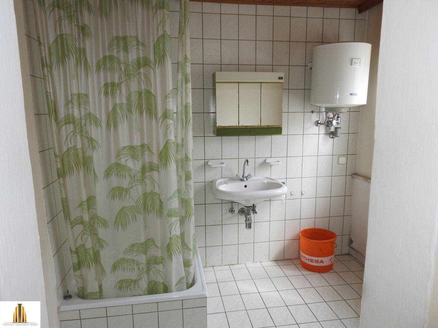 Einfaches Badezimmer mit Badewanne, Duschvorhang und Waschbecken.
