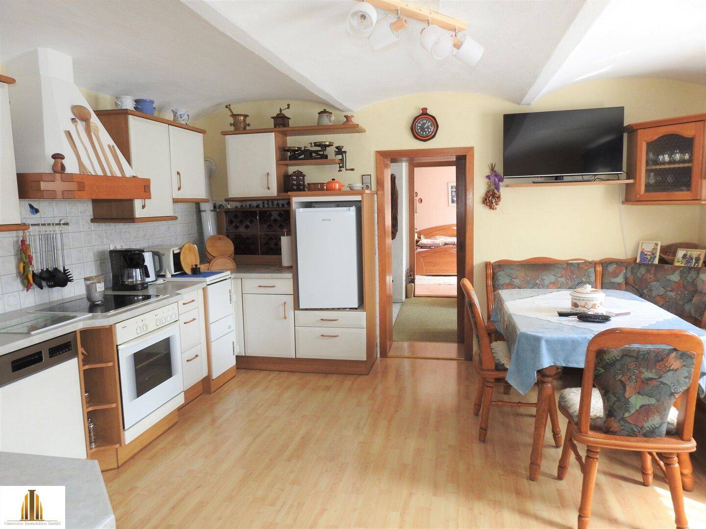 Geräumige Wohnküche mit Holzboden, weiß-braunen Schränken und Essbereich.