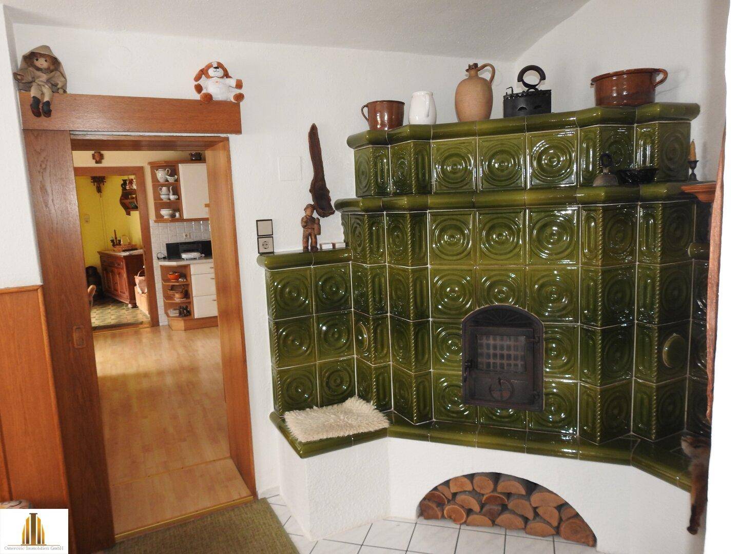 Gemütlicher Raum mit einem traditionellen grünen Kachelofen und Holzboden.