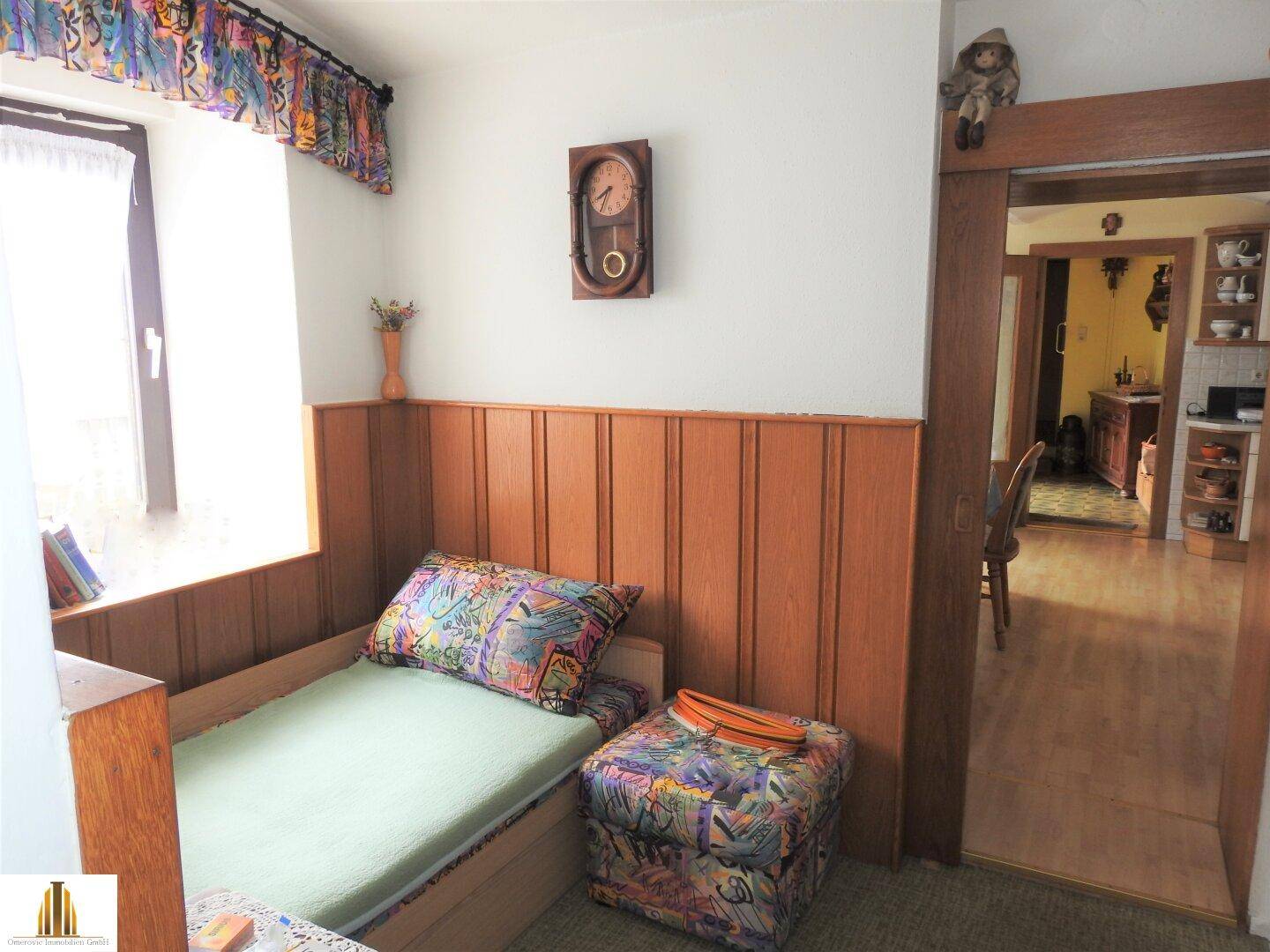 Kleines Schlafzimmer oder Gästezimmer mit Holzvertäfelung und Fenster.