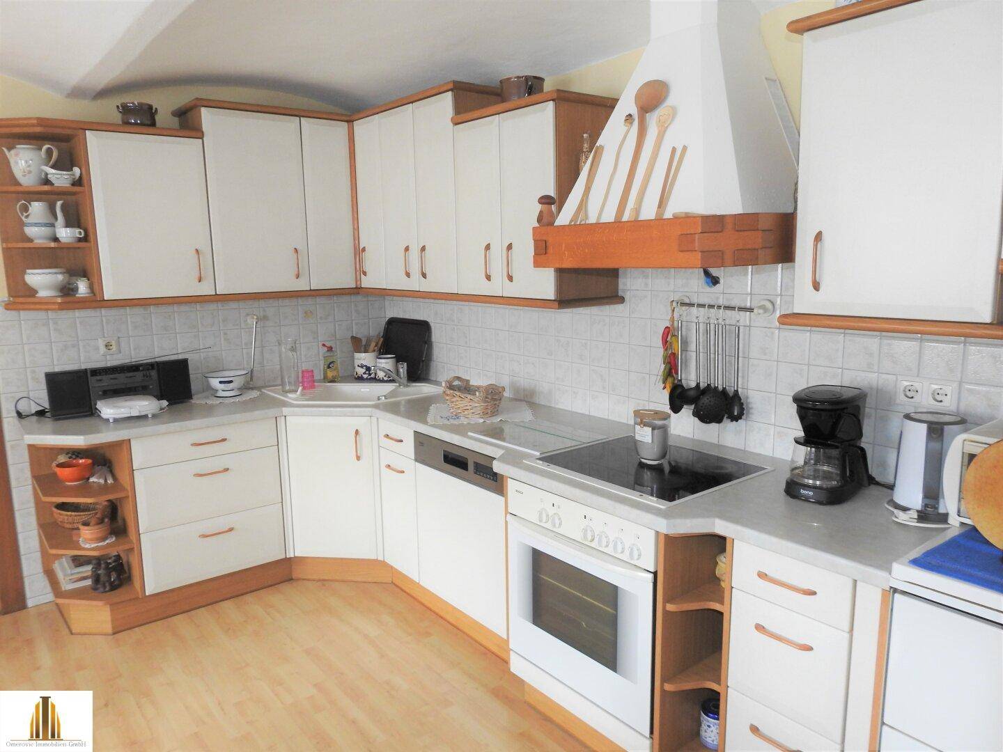 Detailansicht der Küche mit weißen Schränken, integrierten Geräten und Fliesenrückwand.