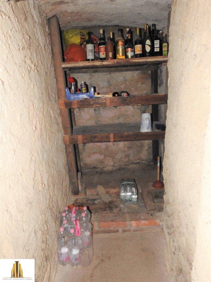 Rustikaler Weinkeller mit einfachen Holzregalen und gelagerten Flaschen.