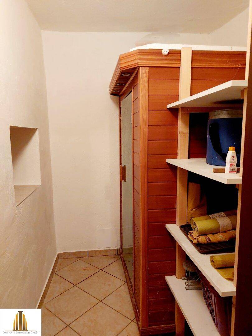 Badezimmer mit einer Holzkabine, die als Sauna oder Infrarotkabine dient.
