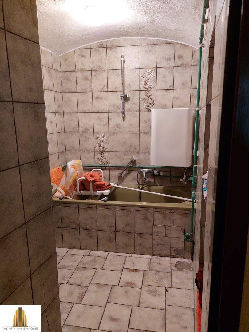 Badezimmer mit Badewanne und Fliesen an Wänden und Boden.