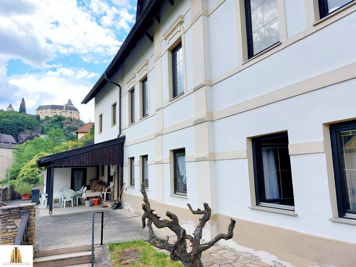 Überdachte Terrasse an der Seite des Hauses mit Blick auf eine Burg in der Ferne.