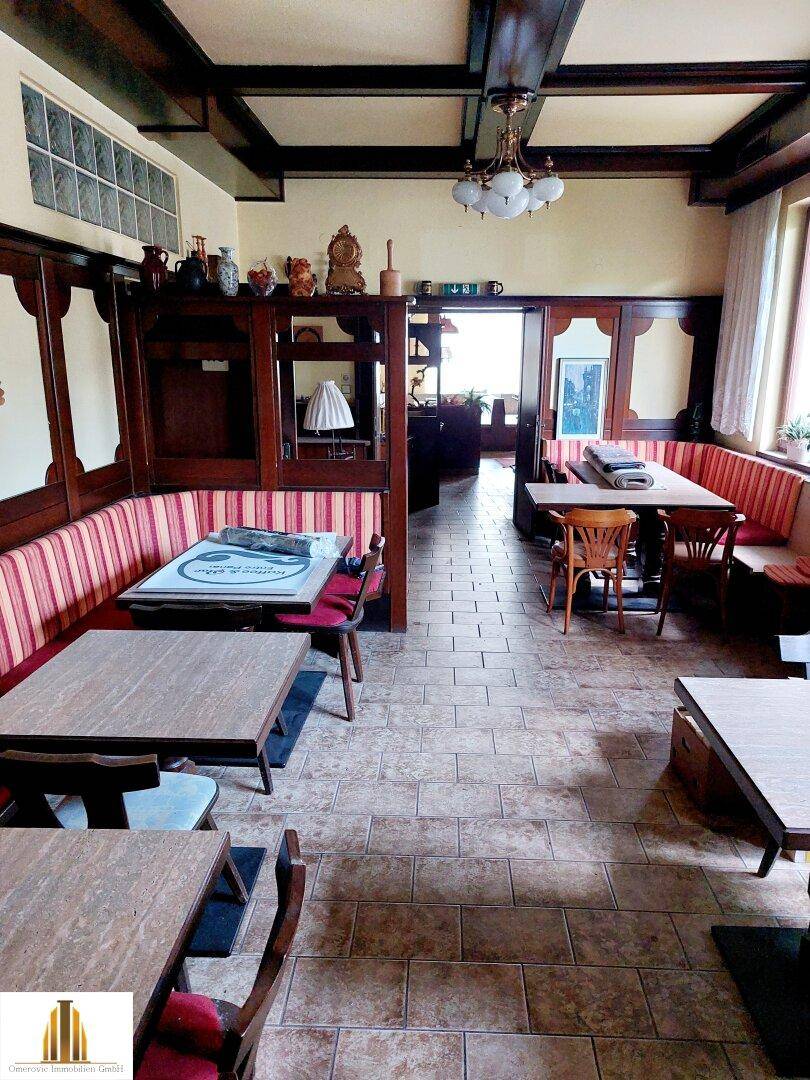 Rustikaler Gastraum mit Holzbalken, gefliestem Boden und gemütlichen Sitzbänken in traditionellem Stil.