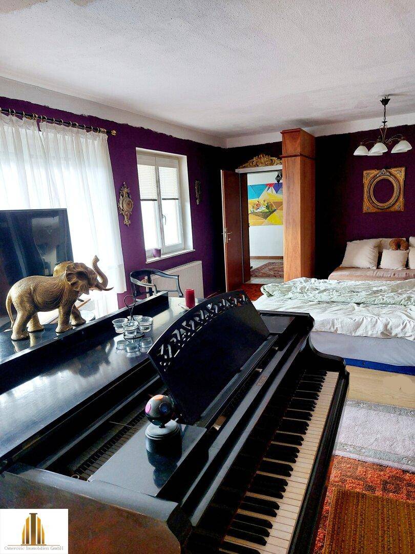 Schlafzimmer mit auffälligen violetten Wänden, einem Flügel und traditioneller Dekoration.