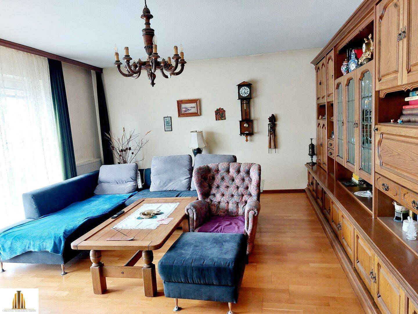 Wohnzimmer mit Holzboden, großer Schrankwand und traditionellen Möbeln.