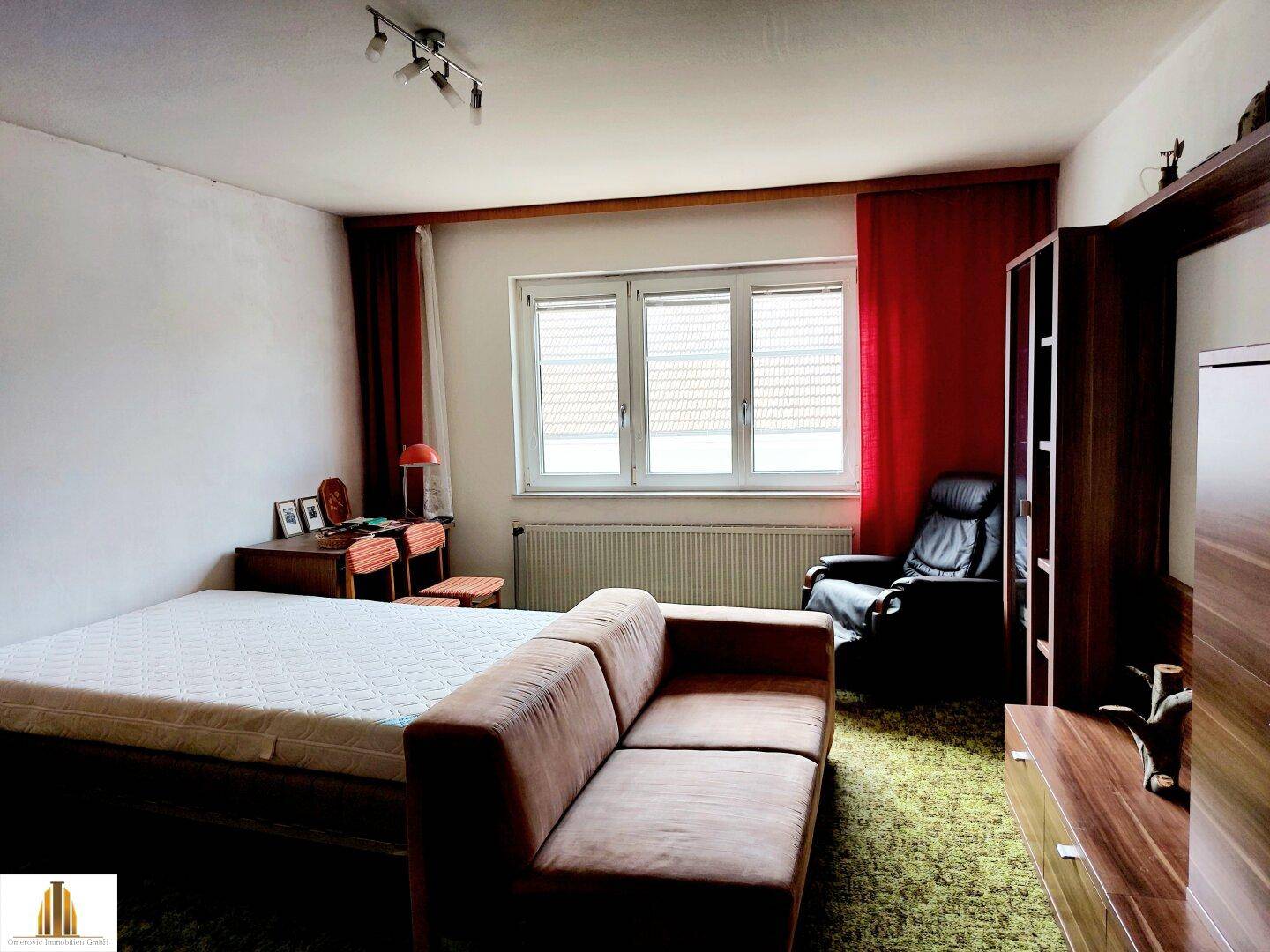 Zimmer mit grünem Teppichboden, Fenster und einem Sofa.