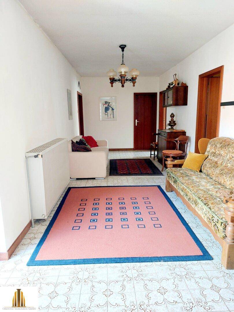 Heller Flur mit gemustertem Teppich, Sofa und traditioneller Einrichtung.