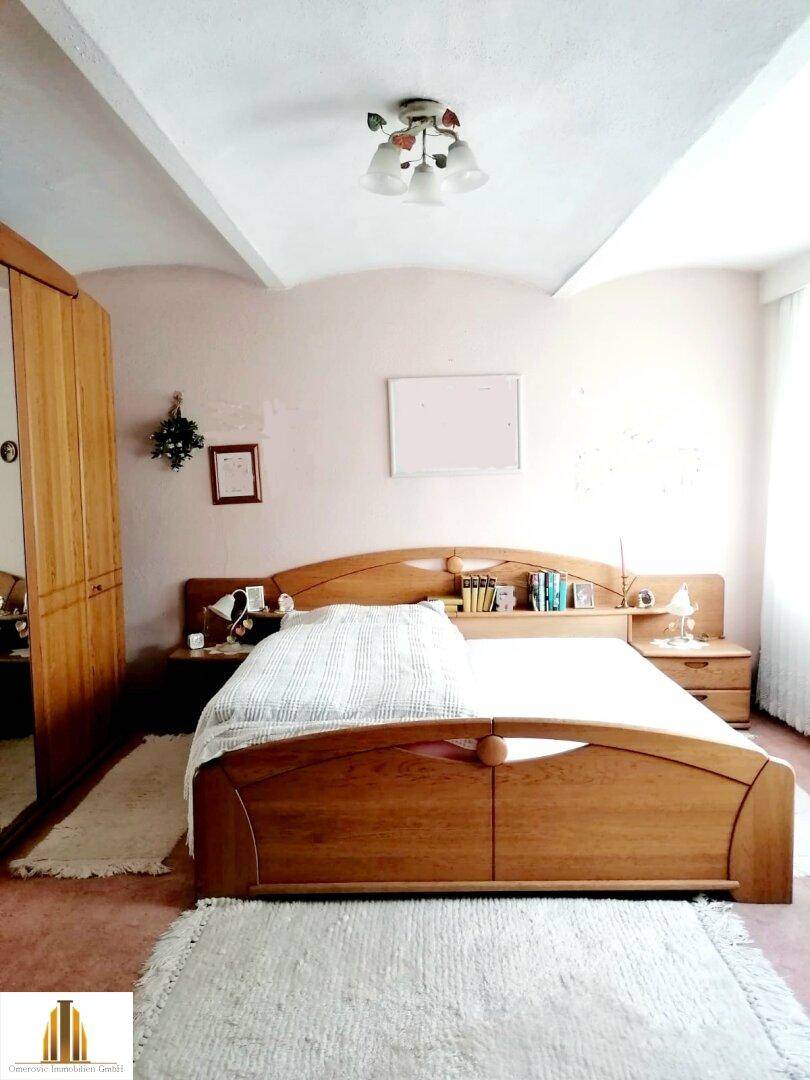 Schlafzimmer mit Doppelbett aus Holz, Teppichboden und schrägen Decken.