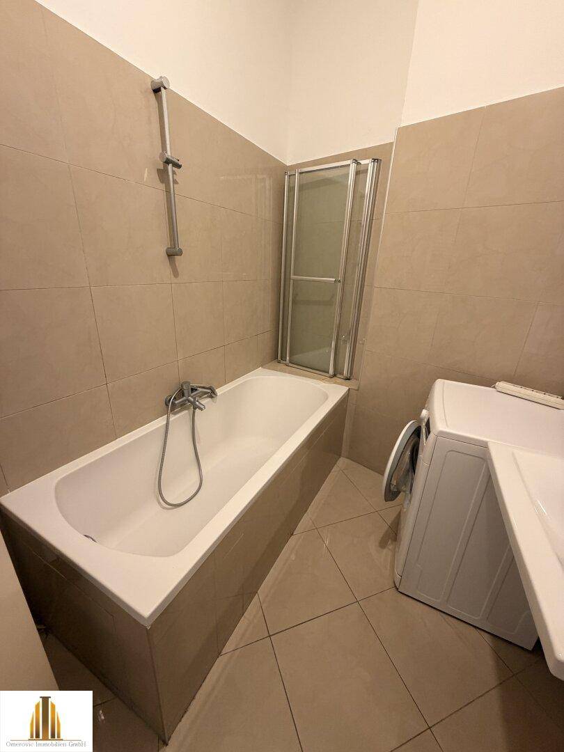 Beige gefliestes Badezimmer mit Badewanne, Duschabtrennung und Waschbecken.